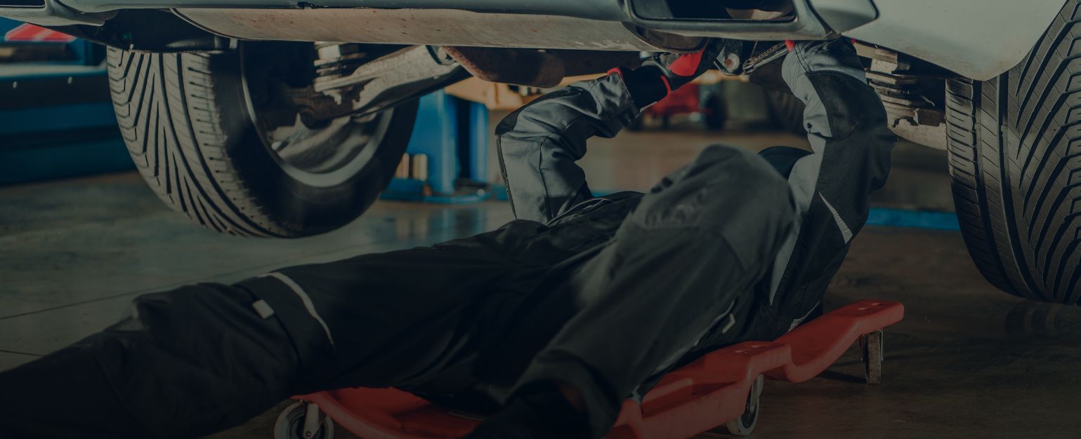 Mechaniker führt eine Unterboden-Inspektion am angehobenen Fahrzeug durch